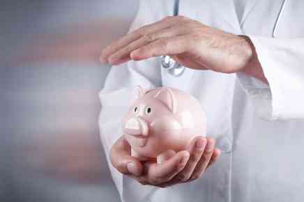 Arzt hält Hand über Sparschwein