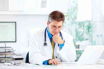 Arzt sitzt vor Laptop